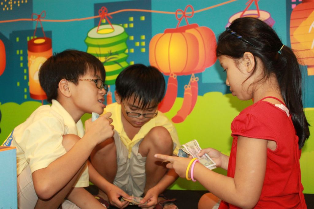 Các bạn nhỏ trao đổi tiền trước phông lồng đèn